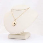Load image into Gallery viewer, Gold locket pendant necklace on a display stand, featuring a sleek, polished finish and delicate chain.