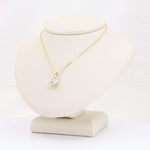 Load image into Gallery viewer, Gold necklace with a crystal pendant, elegantly displayed on a beige bust. Perfect for formal occasions.
