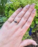 Load image into Gallery viewer, Gold vintage-style ring with blue gemstone, paired with a delicate twisted band, showcased on a manicured hand.