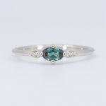 Load image into Gallery viewer, Sleek white gold ring with an oval teal gemstone and two sparkling diamonds on the sides. Elegant and modern design.
