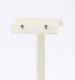 Load image into Gallery viewer, Blue sapphire stud earrings in 14k gold settings on a display stand. Elegant, timeless design for any occasion.