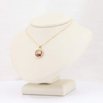Load image into Gallery viewer, Gold pendant necklace with red gemstones, showcasing an elegant teardrop design on a display bust.