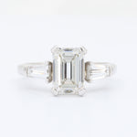Load image into Gallery viewer, Emerald-cut diamond engagement ring with side baguettes, set in sleek white gold. Elegant and timeless design.