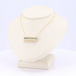 Load image into Gallery viewer, Gold pendant necklace with blue gemstones, modern minimalist design, displayed on a beige jewelry stand.