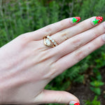 Load image into Gallery viewer, Rose gold three-stone ring featuring sparkling diamonds, worn on a hand with colorful strawberry nail art.