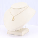 Load image into Gallery viewer, Gold flower pendant necklace on a delicate chain, elegantly displayed on a cream-colored bust.