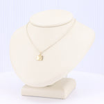 Load image into Gallery viewer, Gold geometric pendant necklace on a silver chain, elegant minimalist design, displayed on a tan jewelry bust.