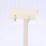 Load image into Gallery viewer, Elegant sterling silver hoop earrings with a polished finish, displayed on a soft beige jewelry stand.