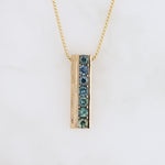 Load image into Gallery viewer, Gold pendant necklace with blue-green gemstones in a sleek, modern rectangular design.