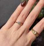 Load image into Gallery viewer, Gold solitaire engagement ring with a round diamond on a hand, paired with a textured gold twist ring.