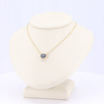 Load image into Gallery viewer, Gold necklace with sapphire pendant on a beige display bust, elegant and stylish for any occasion.