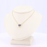 Load image into Gallery viewer, Gold necklace with sapphire pendant on a beige display bust, elegant and stylish for any occasion.