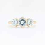 Load image into Gallery viewer, Gold three-stone ring featuring a central light blue gemstone and two matching side stones. Elegant and stylish design.