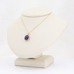 Load image into Gallery viewer, Gold necklace featuring a round purple gemstone pendant on a display bust. Elegant and stylish accessory.