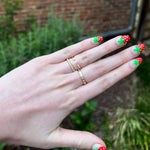 Load image into Gallery viewer, Gold stacking rings with sparkling clear gemstones, worn on a hand with colorful strawberry nail art.