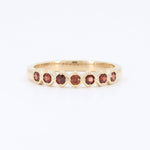 Load image into Gallery viewer, Gold band ring featuring seven garnet gemstones in a chic, vintage-inspired design.