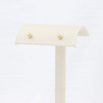 Load image into Gallery viewer, Gold stud earrings displayed on a cream-colored jewelry stand, perfect for everyday elegance.