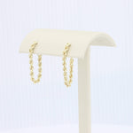 Load image into Gallery viewer, Gold twisted chain drop earrings on a cream display stand. Elegant, modern design perfect for any occasion.