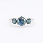 Load image into Gallery viewer, Silver three-stone ring featuring a central blue sapphire and two green-blue sapphires, elegant and contemporary design.