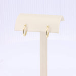 Load image into Gallery viewer, Gold hoop earrings displayed on a beige jewelry stand, featuring a sleek and modern design.