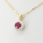 Load image into Gallery viewer, Gold pendant necklace featuring a round ruby centerpiece surrounded by sparkling diamonds. Elegant and stylish accessory.
