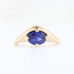 Load image into Gallery viewer, Gold wave-style ring featuring an oval blue sapphire, elegant and modern design.