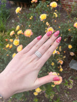 Load image into Gallery viewer, Silver stackable ring with shimmering gemstones, worn on a hand with bright pink glitter nails, surrounded by yellow roses.