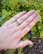 Load image into Gallery viewer, Elegant gold engagement ring with floral accents, paired with manicured light pink nails featuring delicate designs.