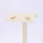 Load image into Gallery viewer, Gold floral stud earrings with light blue opal stones, elegant and stylish for any occasion.
