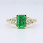 Load image into Gallery viewer, Emerald and diamond ring in yellow gold with an emerald cut center stone and triangular side diamonds.
