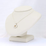 Load image into Gallery viewer, Silver flower pendant necklace with a yellow gemstone on a sleek display stand. Elegant and stylish jewelry piece.