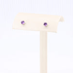 Load image into Gallery viewer, Purple amethyst stud earrings in sterling silver, showcased on a minimalistic display stand.