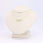 Load image into Gallery viewer, Gold necklace with five aqua gemstones, stylishly displayed on a beige jewelry stand.