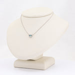 Load image into Gallery viewer, Silver delicate necklace with a rectangular aquamarine pendant on a neutral display stand.