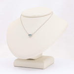 Load image into Gallery viewer, Silver delicate necklace with a rectangular aquamarine pendant on a neutral display stand.