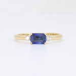 Load image into Gallery viewer, Emerald-cut blue sapphire ring with two diamond accents set in a 14k yellow gold band. Elegant and timeless design.
