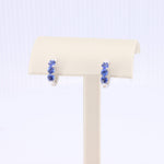 Load image into Gallery viewer, Silver hoop earrings featuring vibrant blue gemstones on a sleek display stand. Elegant and stylish accessory.
