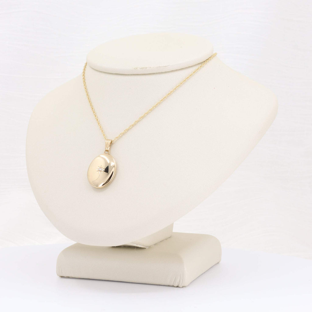 Gold locket necklace on a display, featuring a smooth finish and delicate chain, perfect for elegant styling.