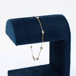 Load image into Gallery viewer, Elegant gold bracelet with sparkling clear crystals, displayed on a navy blue velvet stand.