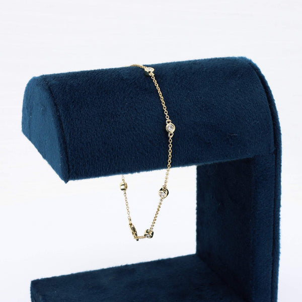 Gold-plated bracelet with sparkling clear crystals, displayed on a navy velvet stand. Elegant and stylish accessory.