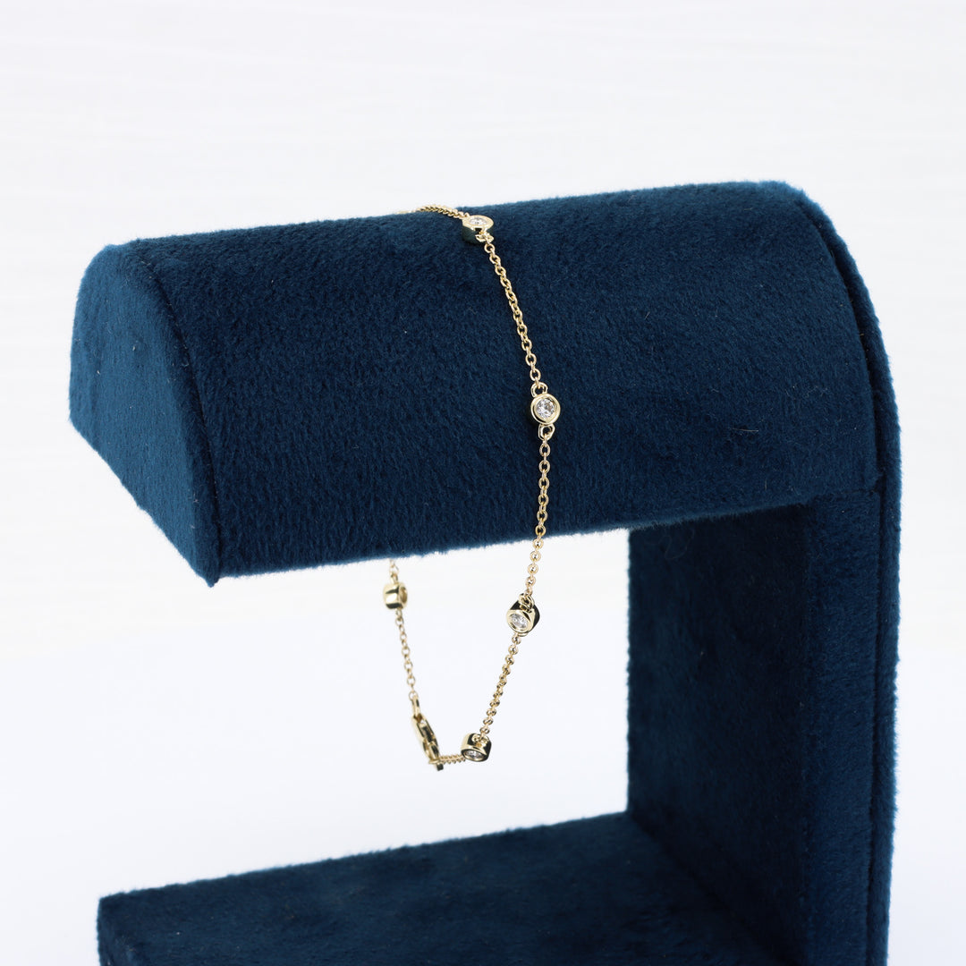 Elegant gold bracelet with sparkling clear crystals, displayed on a navy blue velvet stand.