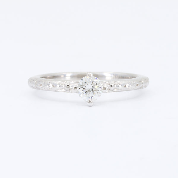 Elegant white gold engagement ring with a round diamond centerpiece and intricate filigree detailing.
