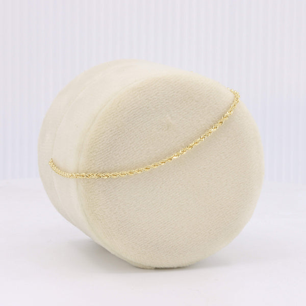 Cream fabric display with a delicate gold braided chain bracelet, showcasing elegant style for jewelry enthusiasts.