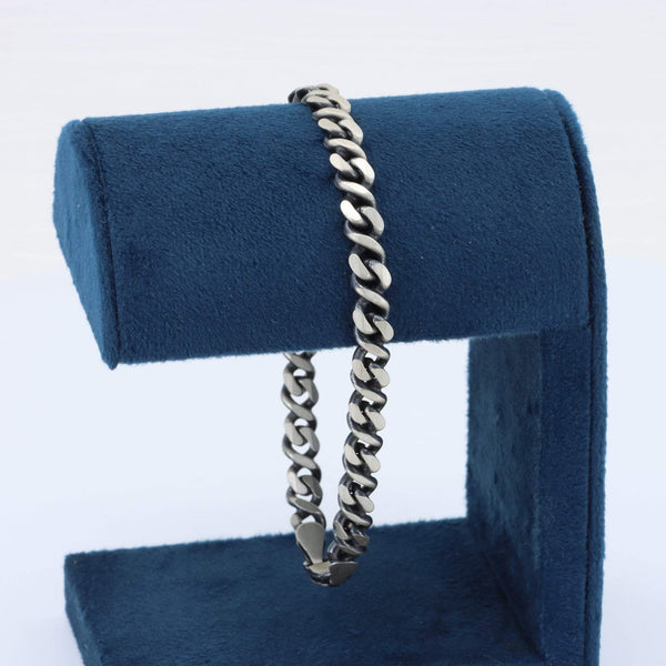 Men's silver stainless steel chain bracelet on a blue velvet display stand, sleek and stylish design.