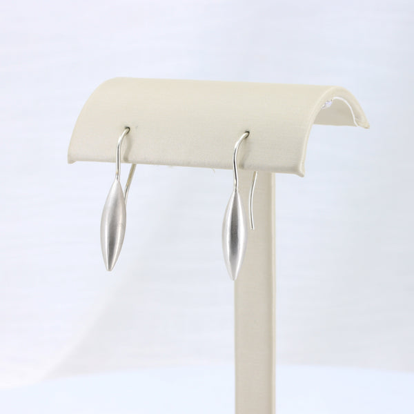Sleek silver drop earrings in a modern, minimalist design on a display stand.