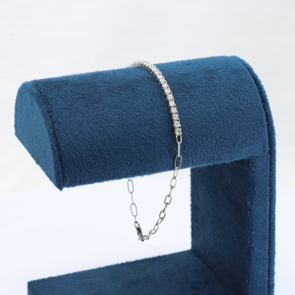 Silver diamond tennis bracelet on a blue velvet display stand. Elegant and modern design with a secure chain clasp.