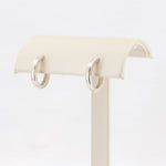 Load image into Gallery viewer, Silver hoop earrings displayed on a beige jewelry stand, featuring a sleek, polished finish.