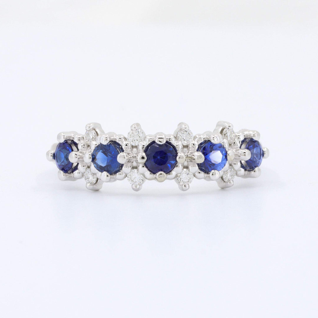Elegant silver band ring with blue sapphires and shimmering diamonds, perfect for any occasion.