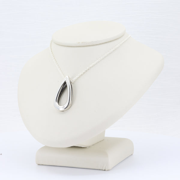 Silver teardrop pendant necklace with sleek design on a delicate chain, resting on a soft display bust.